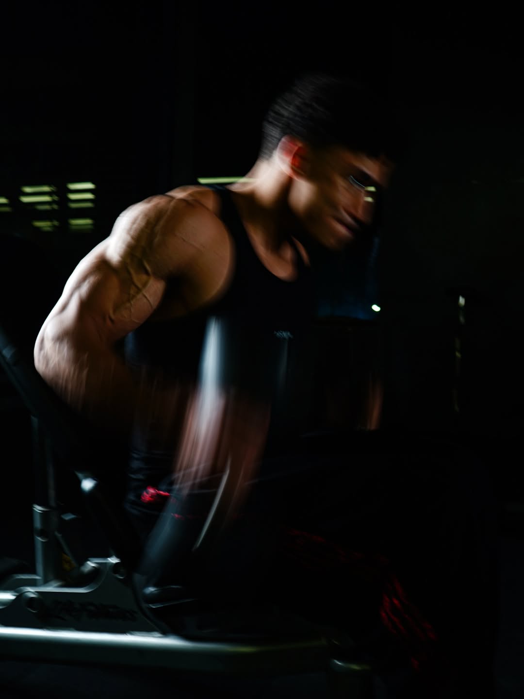 Male athlete in athletic training gear performing intense workout in gym, dramatic lighting
