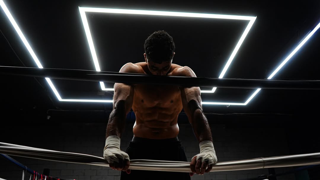 Athlete in dark athletic training wear performing heavy barbell training in a gym, dramatic lighting